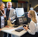 Travel agent assisting customer booking flight on computer